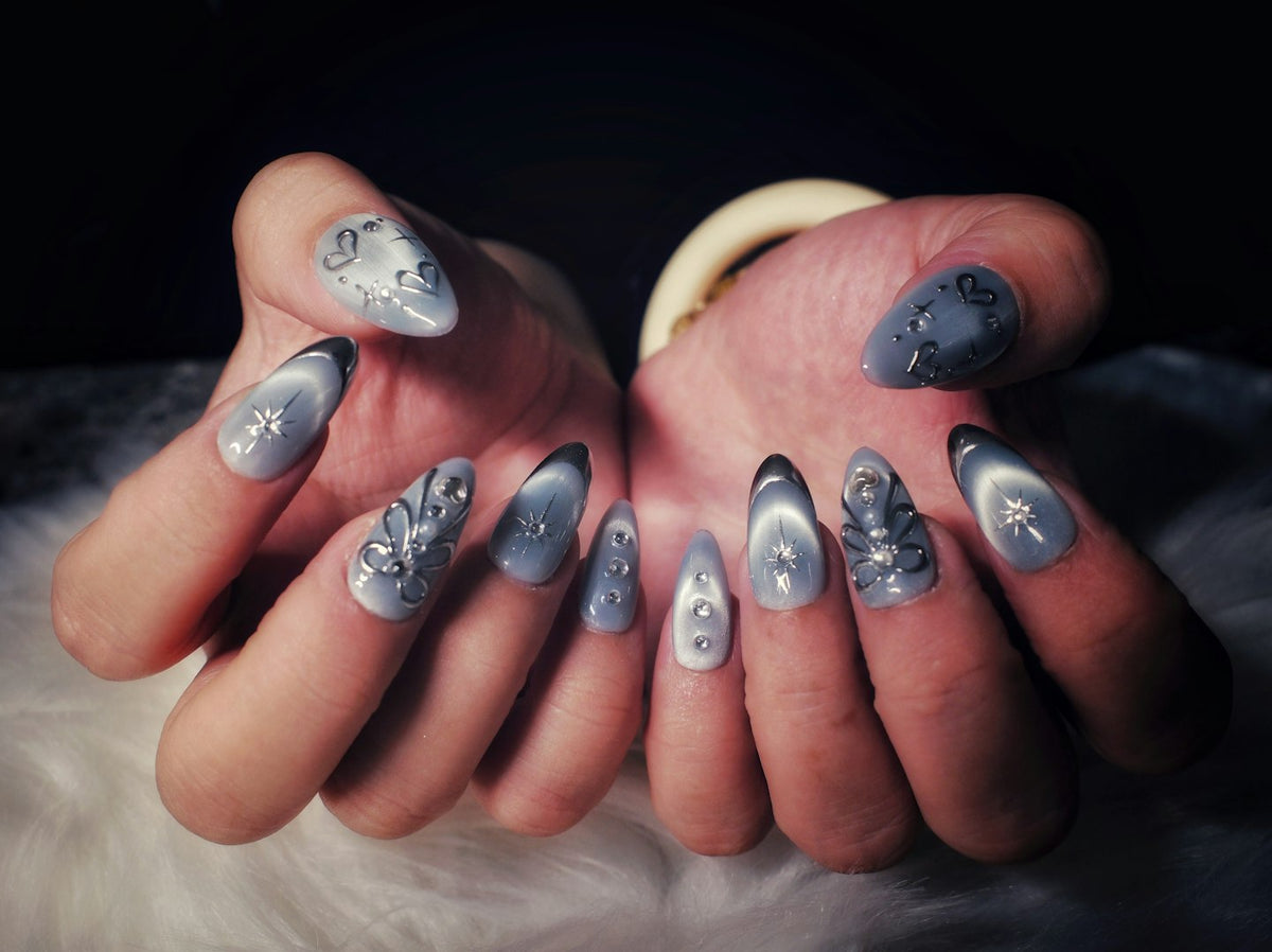 Hands with grey cat eye nails decorated with small rhinestones on white fur