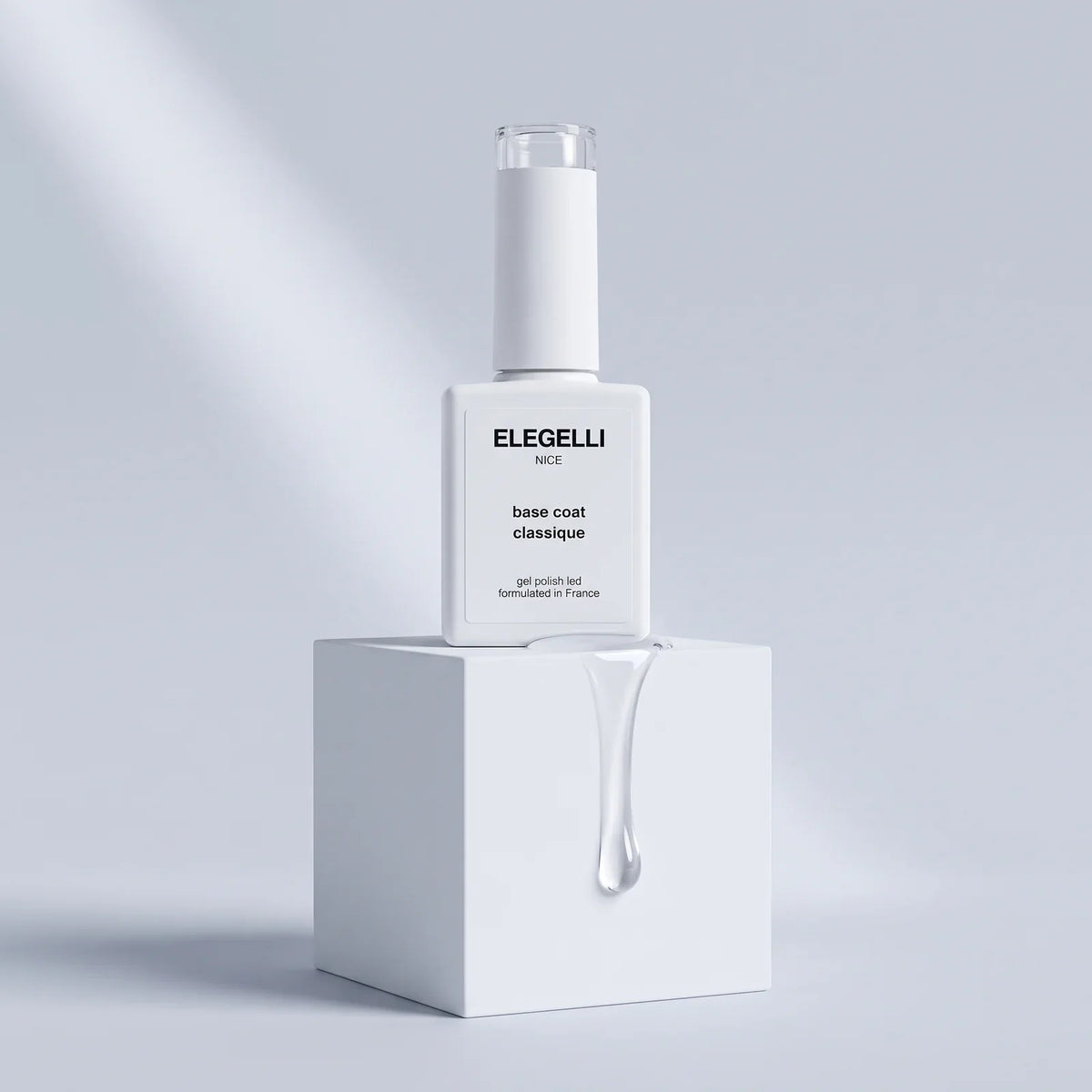 Elegelli Classic Base Coat bottle on a white cube with a clear gel drop