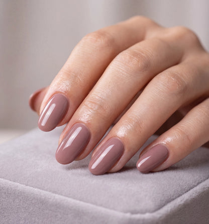 Hand with mauve nail polish on a neutral background