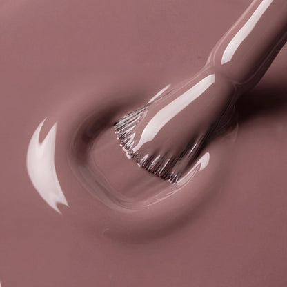 Close-up of a makeup brush with brown nail polish on a matching background