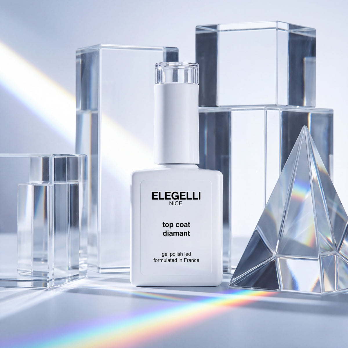 Flacon de Diamond Top Coat Elegelli entre des blocs de verre transparent et un prisme qui projette un arc-en-ciel