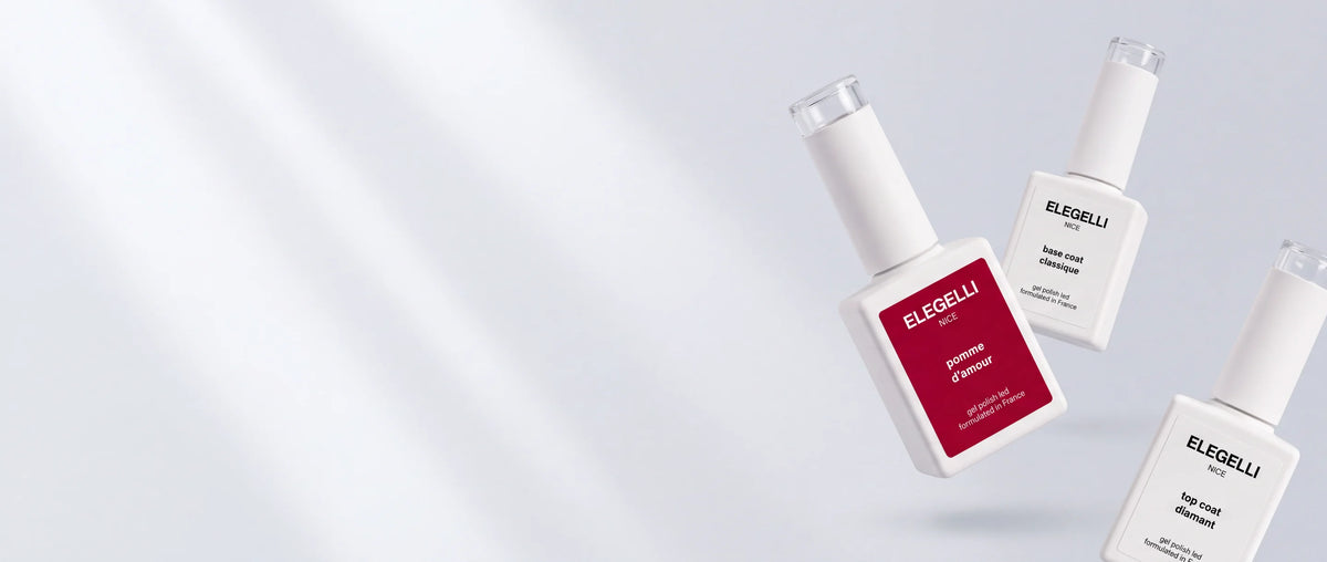 Main avec une manucure nude brillante tenant un flacon de Diamond Top Coat Elegelli